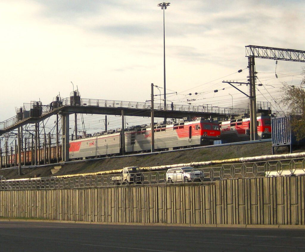 Russische Güterzüge am Bahnhof von Ulan-Ude. Fotografiert von Hauptstraße. Über die Züge führt eine Brücke.