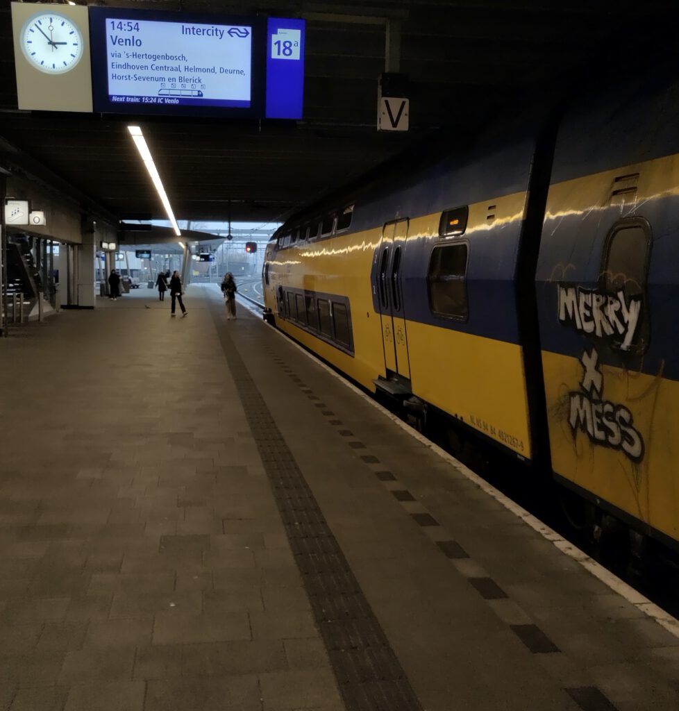 Bahnsteig am Bahnhof Utrecht. Rechts im Gleis steht ein blau-gelber IC der niederländischen Bahn. 