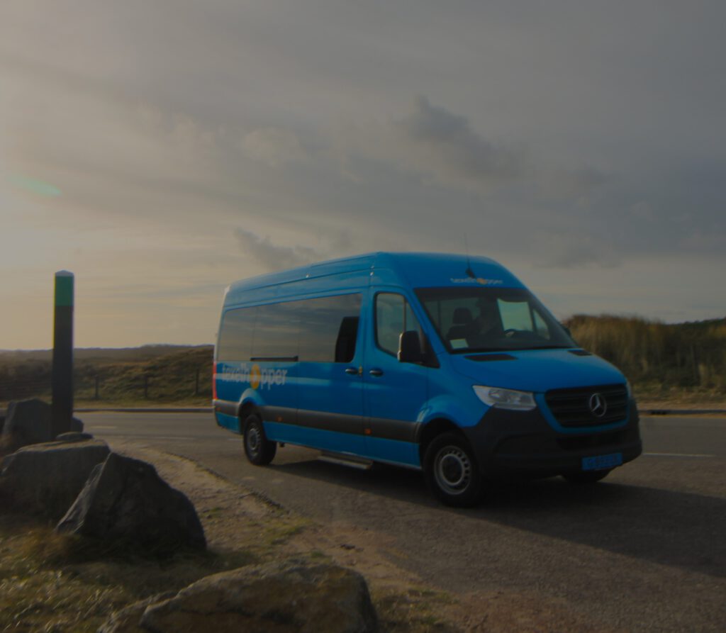 Texelhopper: Blauer Minibus steht an einer Haltestelle in den Dünen von Texel. 