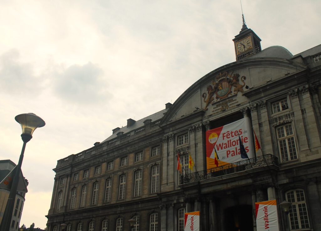 Nahaufnahme des Palais des Princes-Evêques in Lüttich. Über dem Eingang bunte Werbung für die Fetes de Wallorie.