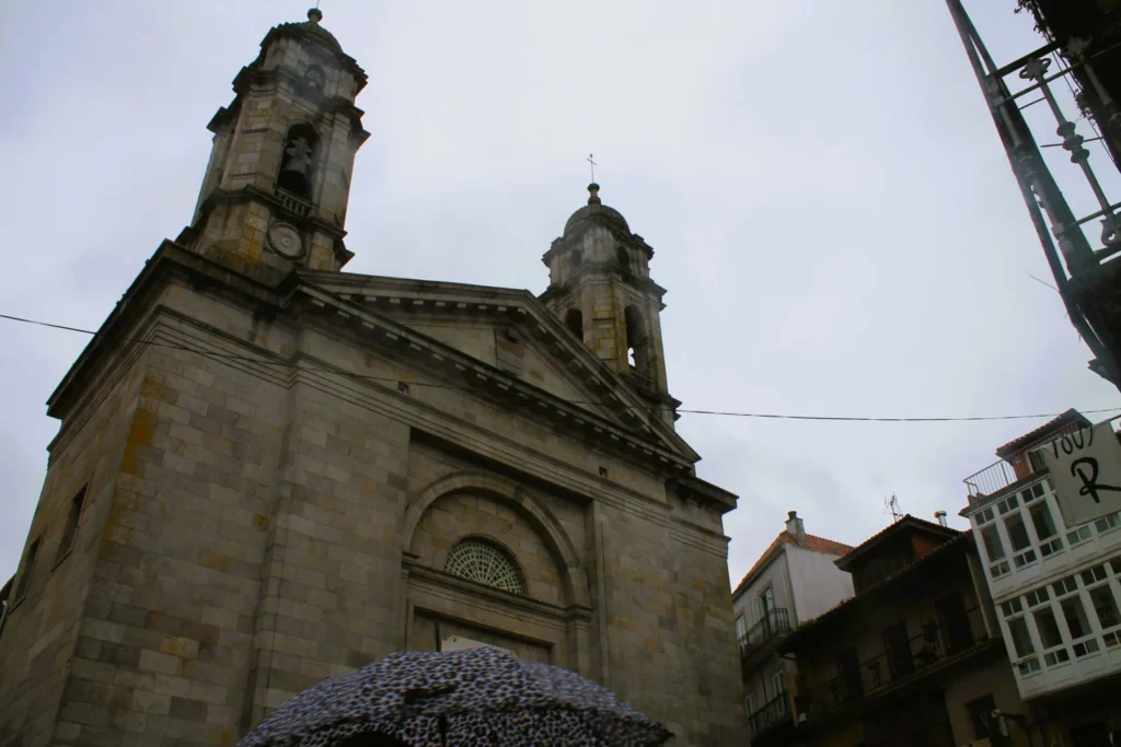 Die Basílica de Santa María in Vigo von vorne mit ihren zwei barocken Türmen bei bewölktem Himmel.