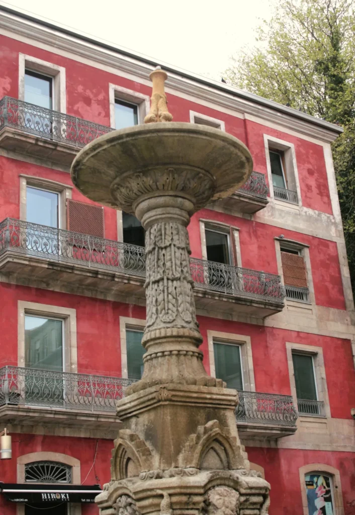 Charafiz Brunnen aus Sandstein vor klassizistischem, rotem Gebäude in Vigo.