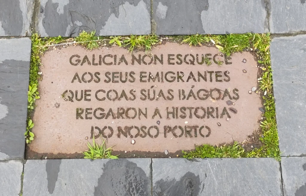 Steinplatte mit der galicischen Inschrift "Galicia non esquece aos seus emigrantes. Que coas suas bagoas regarona historia do noso porto"