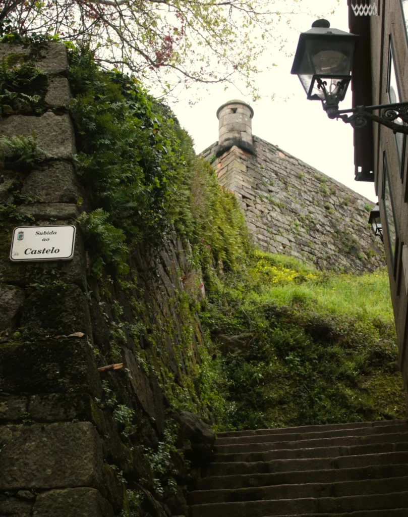 Treppen hoch zum Castelo de San Sebastián, mig Grün bewachsenen Mauern.