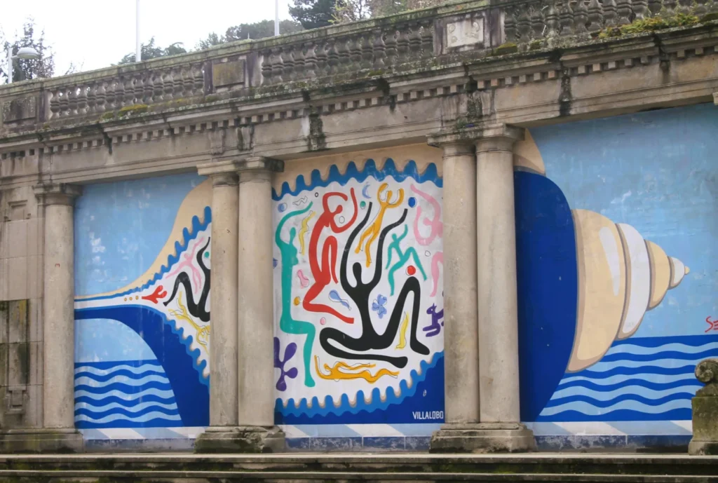 Bunte Streetart an alter Mauer mit Säulen. Darstellung einer Muschel und bunten Figuren im Inneren.