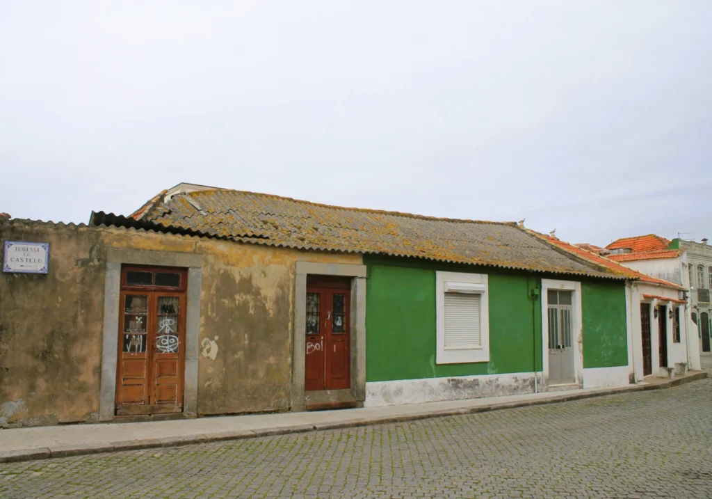 Matosinhos. Flache, alte Häuser an Kopfsteinpflaster-Straße. Ein Haus ist grün.